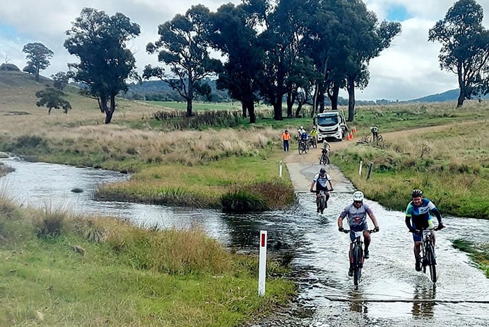 Tour De Rocks cyclists navigating flooded creek