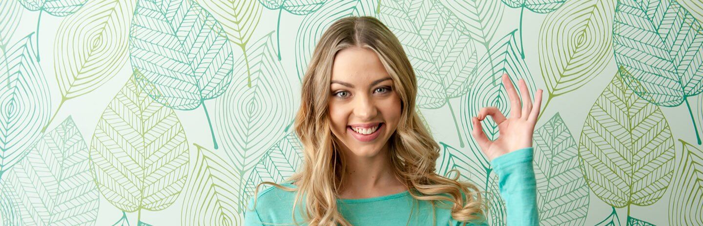 Young women smiles and gestures the OK sign with her hand