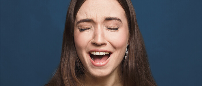Woman laughing to camera in front of blue background